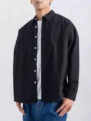 Black long sleeve button-up shirt with white buttons, worn over a white t-shirt.