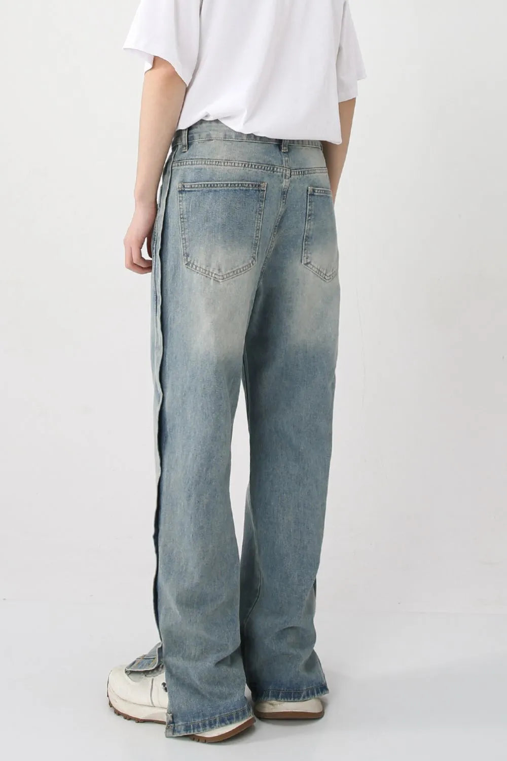 Medium wash baggy denim jeans with side slit and snap hem detail.