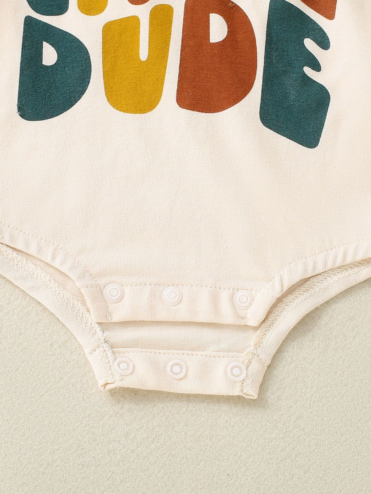 Baby bodysuit in beige with colorful "DUDE" graphic and snap closure
