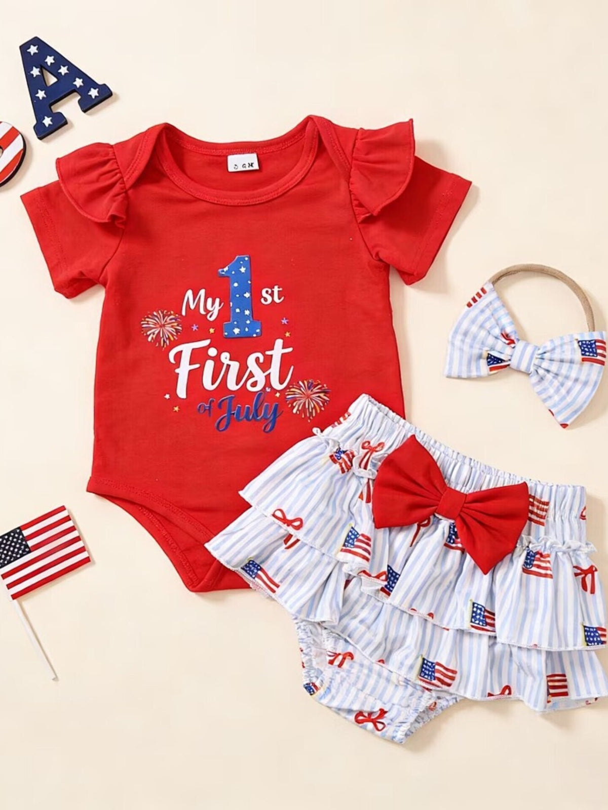 Red baby onesie with "My 1st of July" graphic, striped bloomers with flag print, and matching headband.
