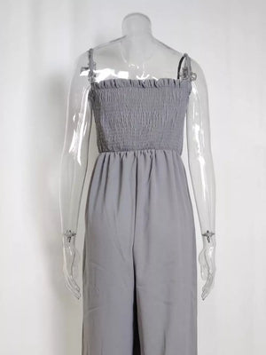 Gray smocked wide leg romper with adjustable spaghetti straps and wide legs.