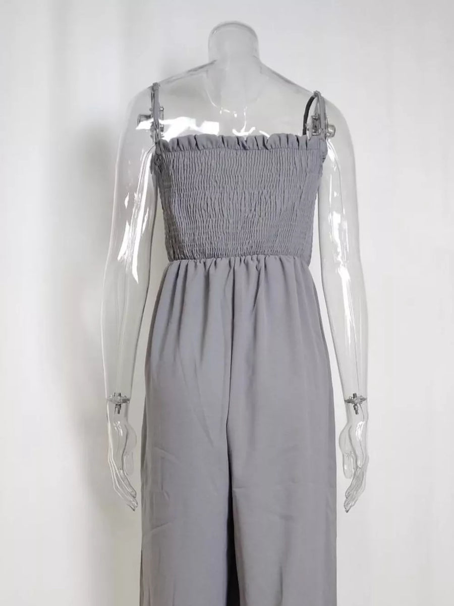 Gray smocked wide leg romper with adjustable spaghetti straps and wide legs.