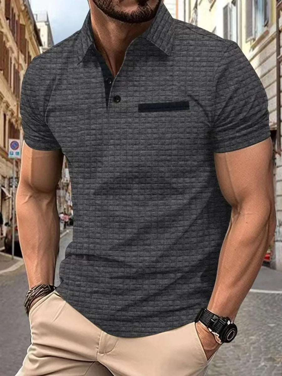 Dark gray textured polo shirt with contrast pocket detail and short sleeves.