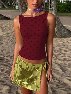 Wine red polka dot tank top with boat neck, styled with a sequined green mini skirt.