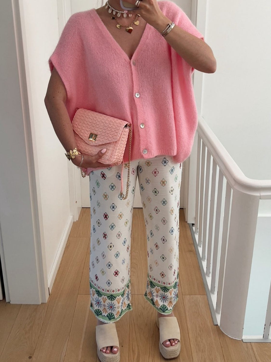 Pink mohair cap sleeve cardigan with pearl buttons, styled with patterned pants and a pink woven crossbody bag.