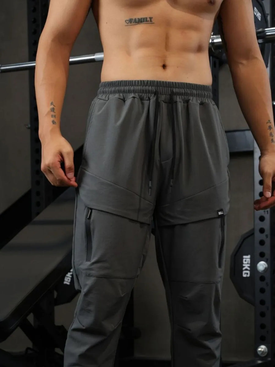 Gray technical joggers with zip pockets and drawstring waist.