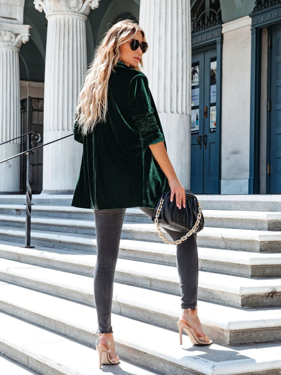 Dark green velvet blazer with drape front and button detail, worn by a model with a black handbag.