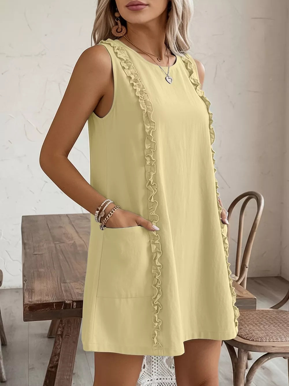 Pastel yellow sleeveless dress with frill detail and pockets.