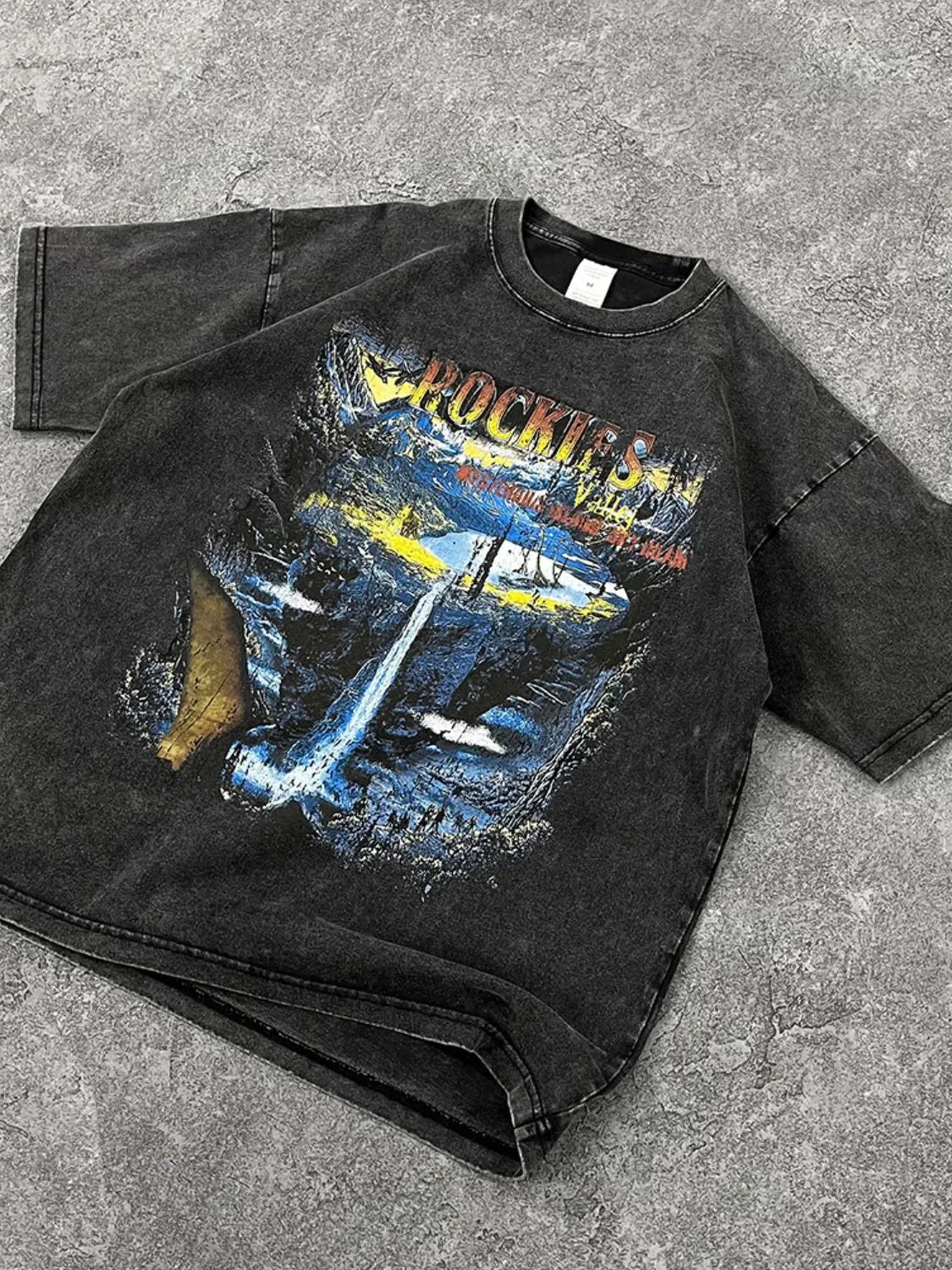 Black vintage wash t-shirt with a graphic print of the Rockies mountains and waterfall.