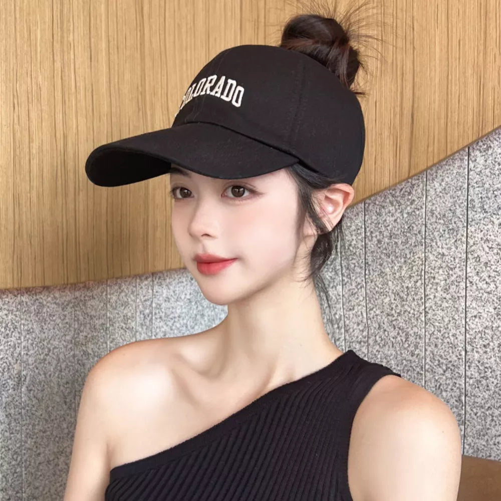 Black cotton visor hat with white Colorado embroidery and a messy bun cutout.
