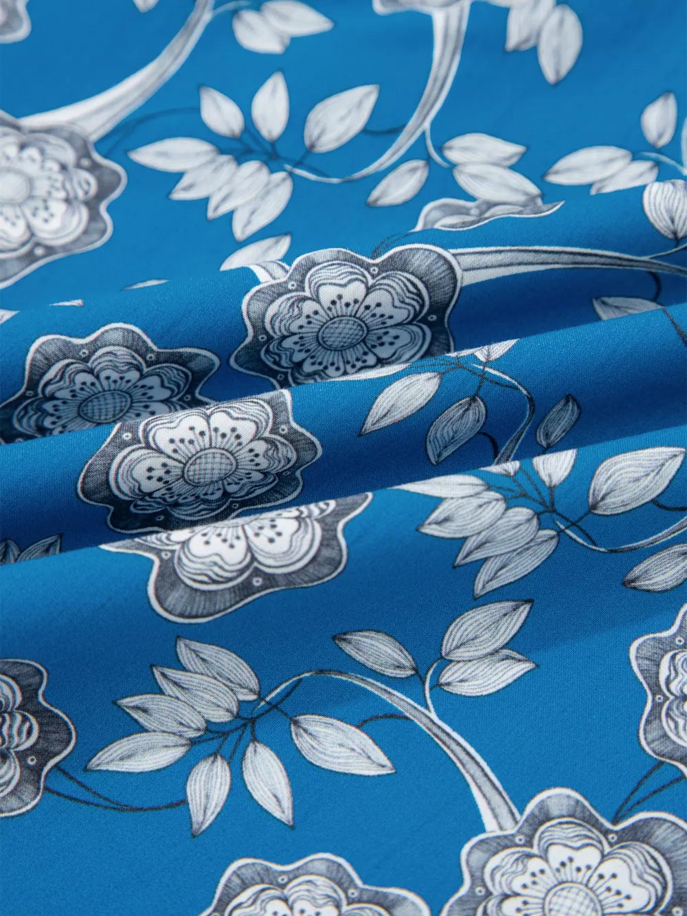 Blue cotton blouse with a floral pattern and ruffle sleeves.