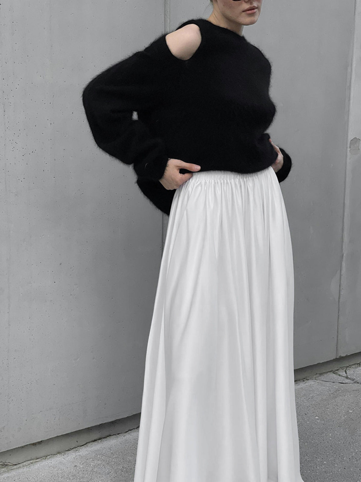 White high-waisted maxi skirt with pockets and a flowy silhouette, styled with a black sweater.