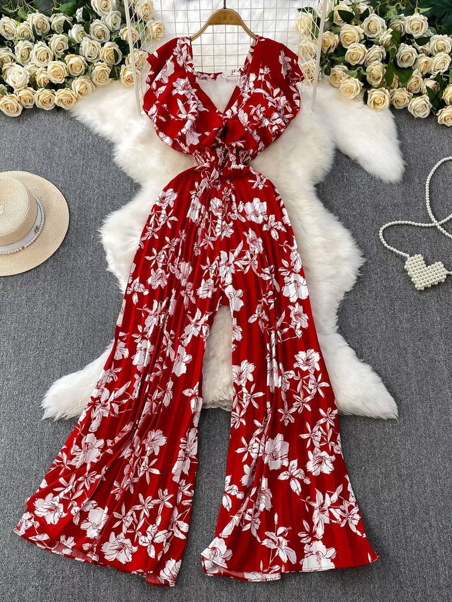 Red floral pleated wide-leg romper with V-neck and smocked waist.