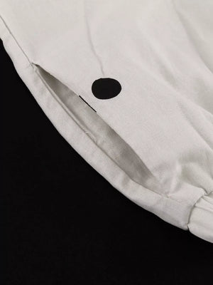 White linen pants with black polka dots and a side pocket.