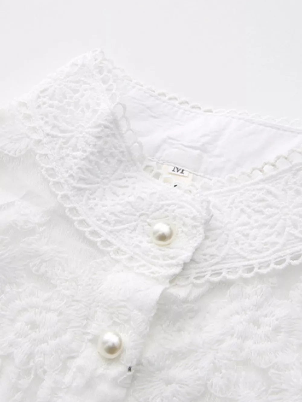 White lace-embellished maxi dress with pearl buttons and lantern sleeves.