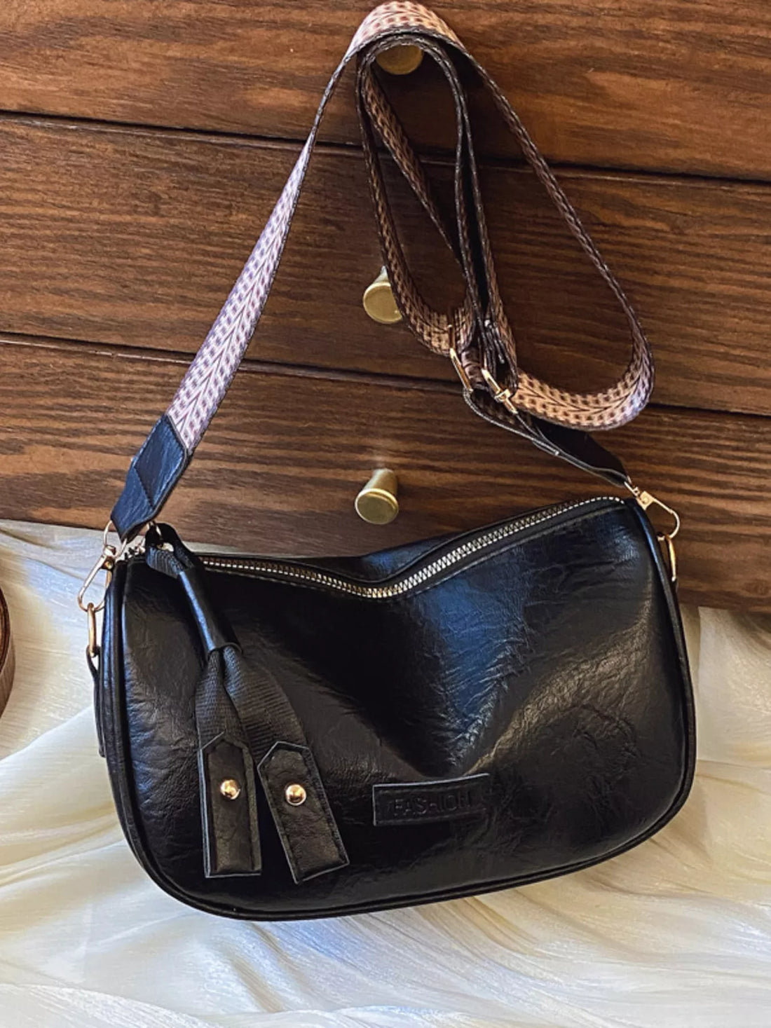 Black crossbody bag with patterned strap and zip closure