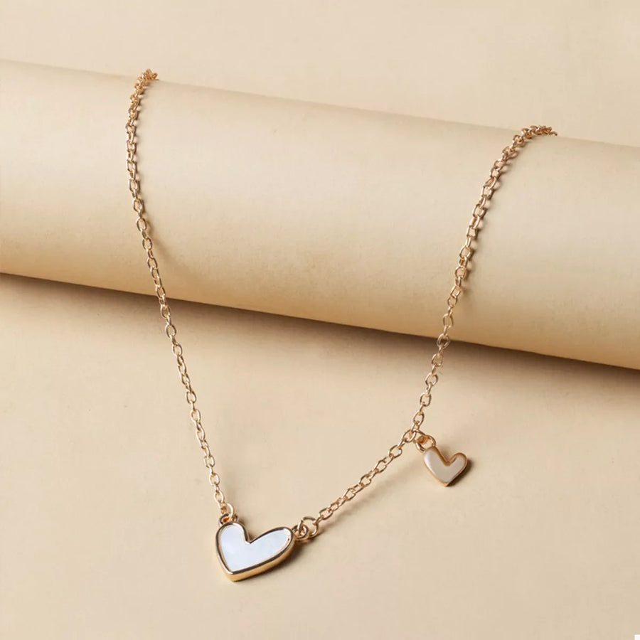 Gold necklace with two white heart pendants, one larger than the other.