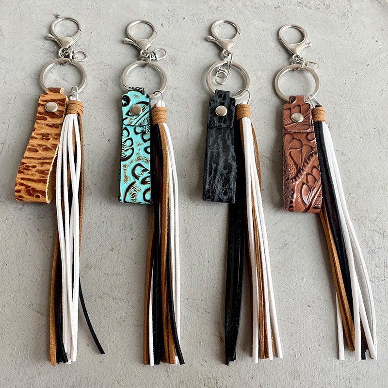 Textured leather tassel keychains in camel, aqua, black, and brown with multi-color fringe.