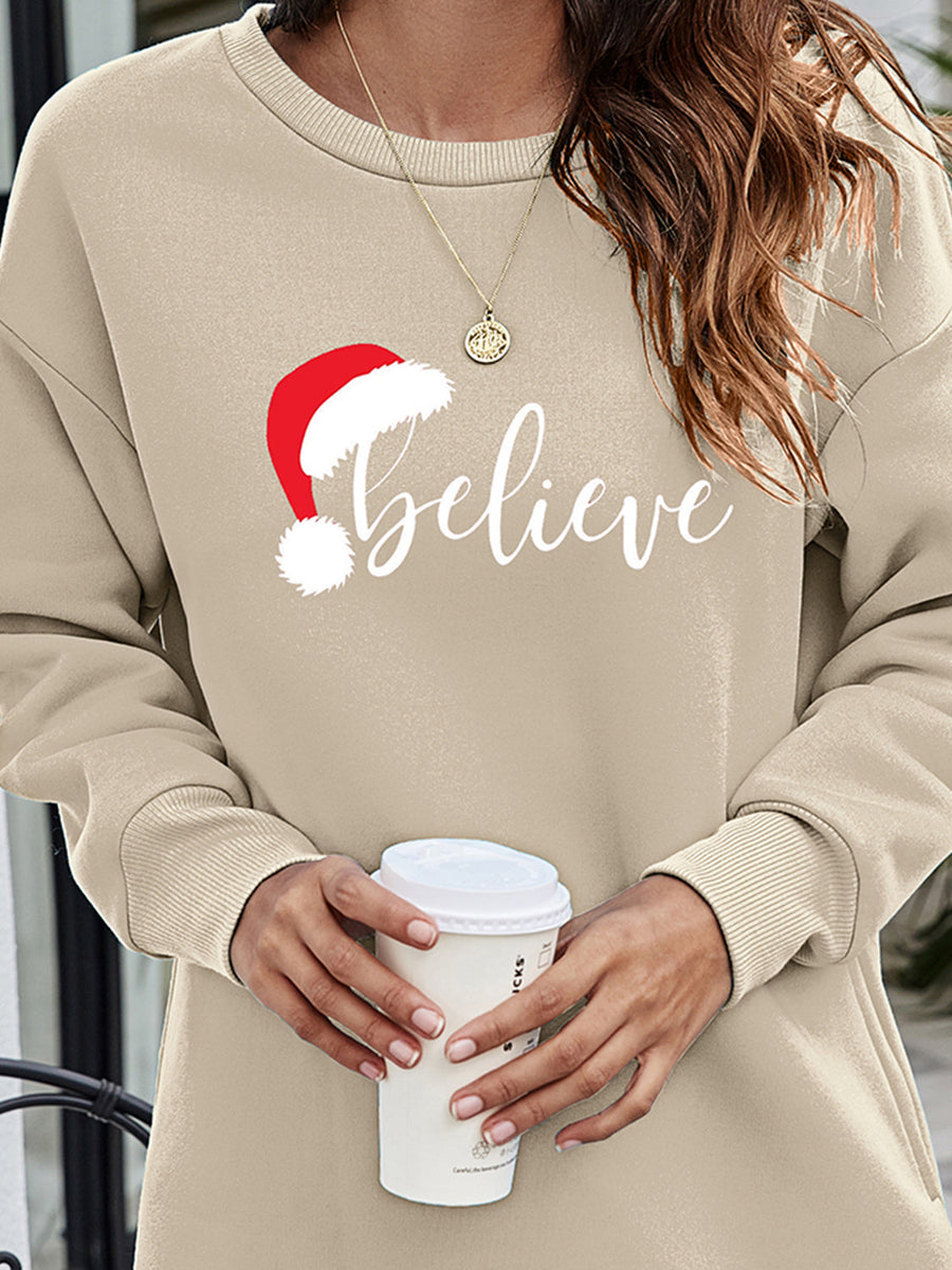 Beige Christmas graphic tunic sweatshirt with Santa hat and "believe" text, crewneck, long sleeves.