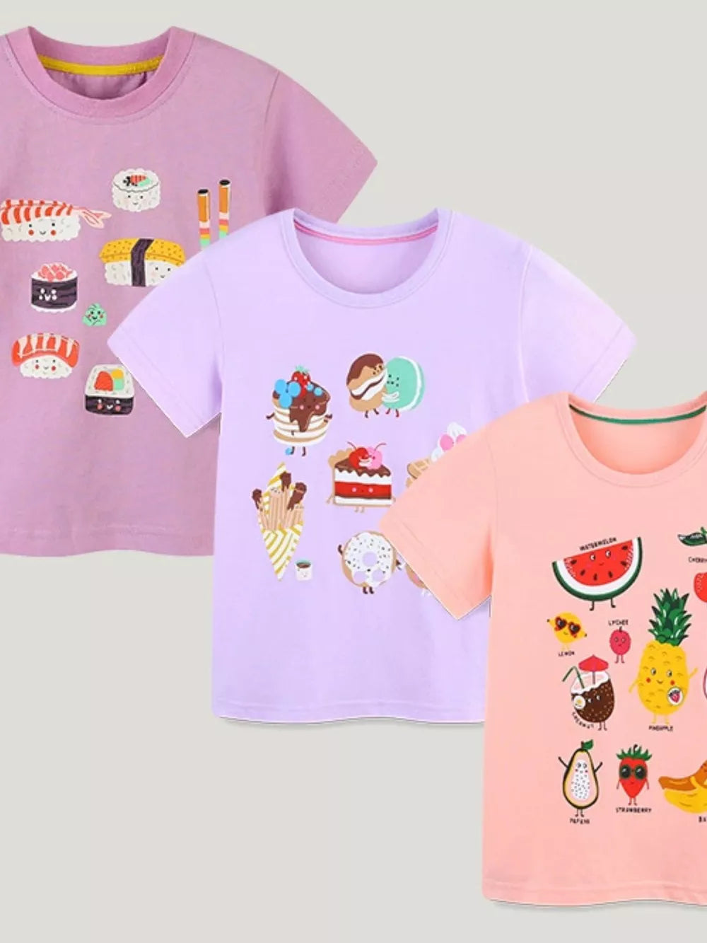 Toddler cotton t-shirts in pink, lavender, and peach with playful cartoon sushi, dessert, and fruit prints.
