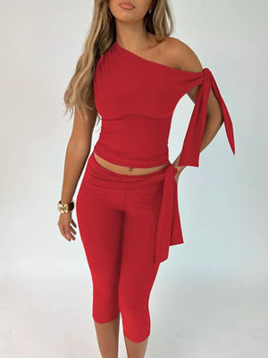 Red asymmetrical one-shoulder top with tie sleeves and matching capri pants.