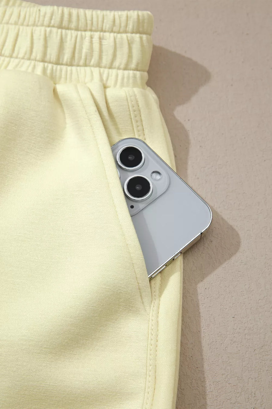 Yellow two-piece set shorts with elastic waistband and a phone in the pocket
