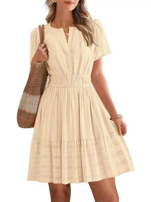 Textured apricot V-neck tiered dress with smocked waist and short sleeves.