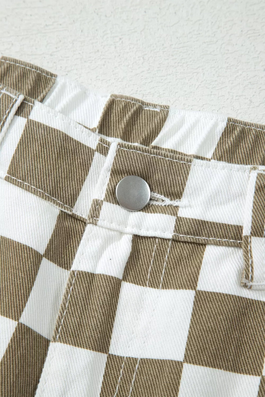 Maternity barrel pants in brown and white checkered denim with a silver button closure.