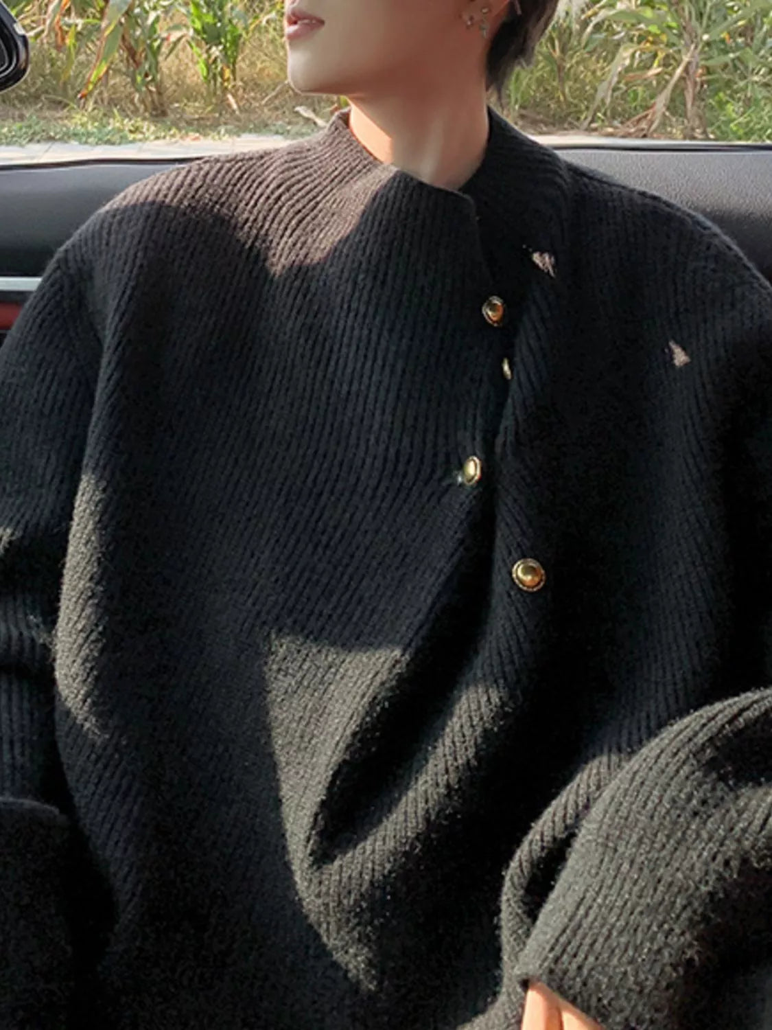 Black knit sweater with gold button accents and a mock neck.