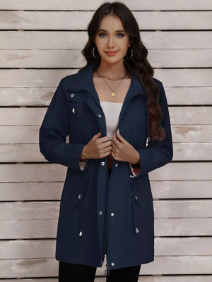 Navy blue drawstring trench coat with snap-down front and plaid lining detail.