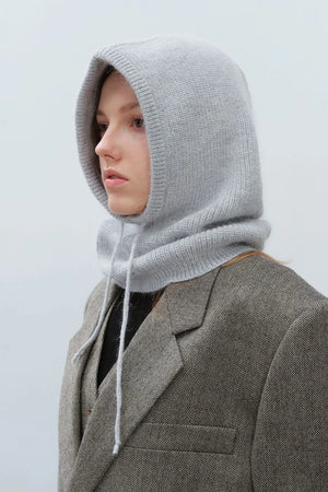 Light gray knit balaclava with hood and drawstring, worn over a blazer.
