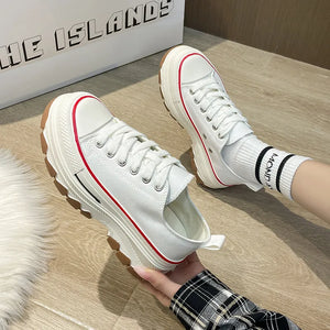 White canvas tread sneakers with red trim and chunky rubber soles.