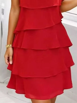 Scarlet tiered ruffle dress with petal sleeves and a gold bracelet.