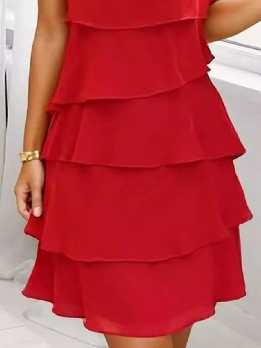 Scarlet tiered ruffle dress with petal sleeves and a gold bracelet.