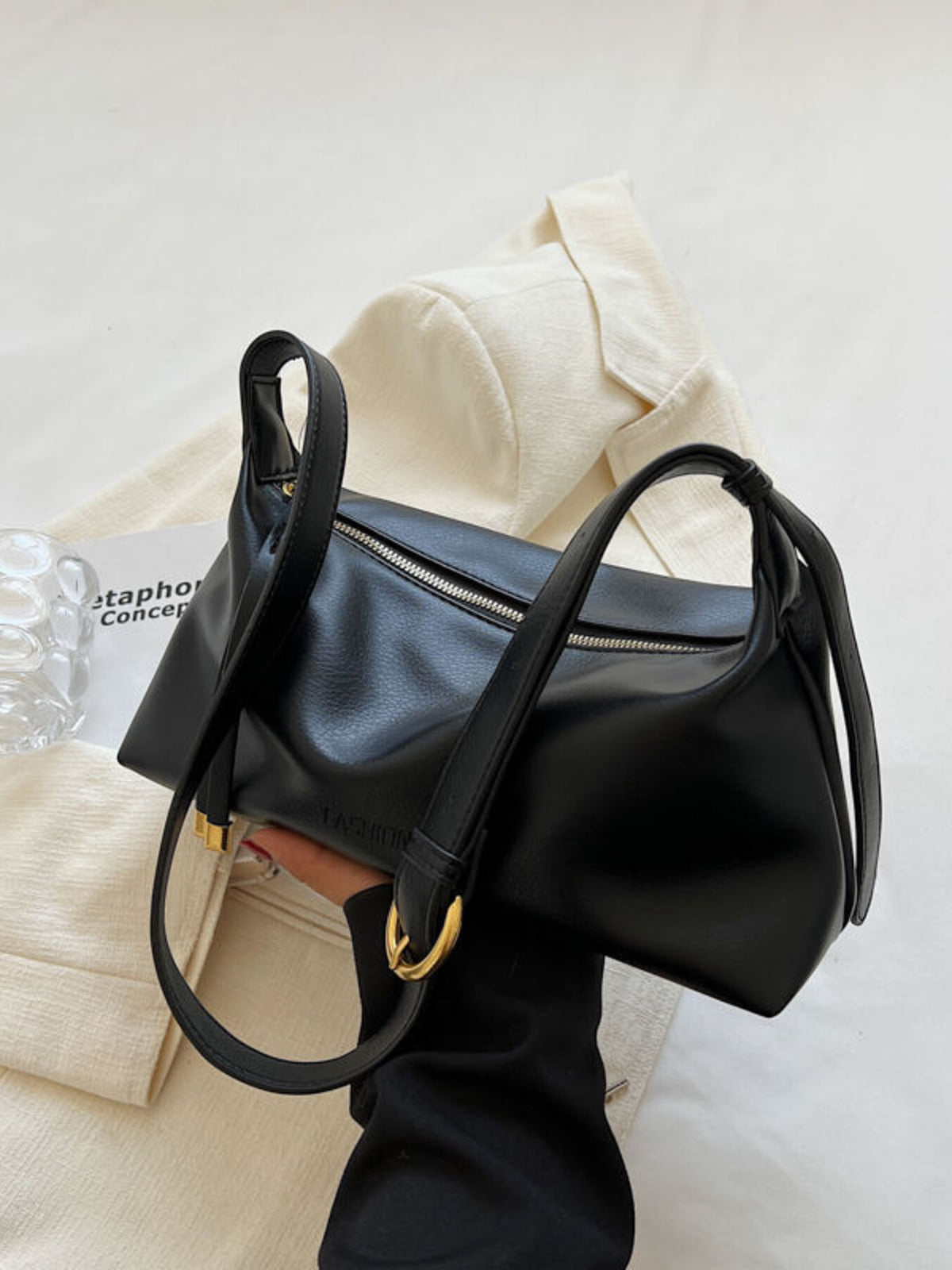 Black slouchy crossbody bag with adjustable strap and gold buckle detail