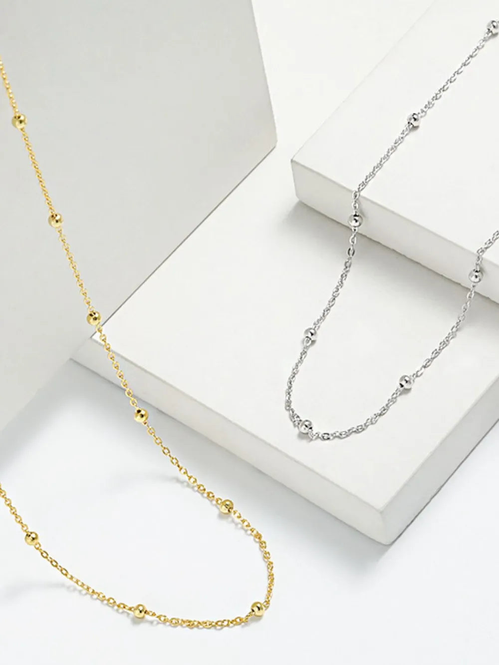 Delicate orb chain necklace in gold and silver with small beaded accents.