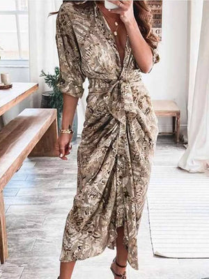 Elegant tie-waist midi dress in a tan and brown abstract print with a deep V-neck and ruched skirt.
