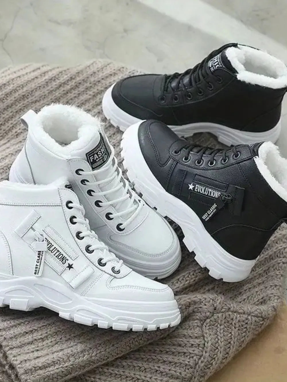 Evolutionary platform boots in black and white with faux shearling lining and chunky soles.