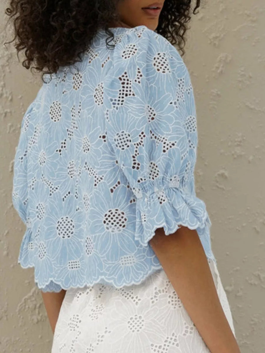 Blue eyelet crop top with white floral embroidery and ruffled sleeves.