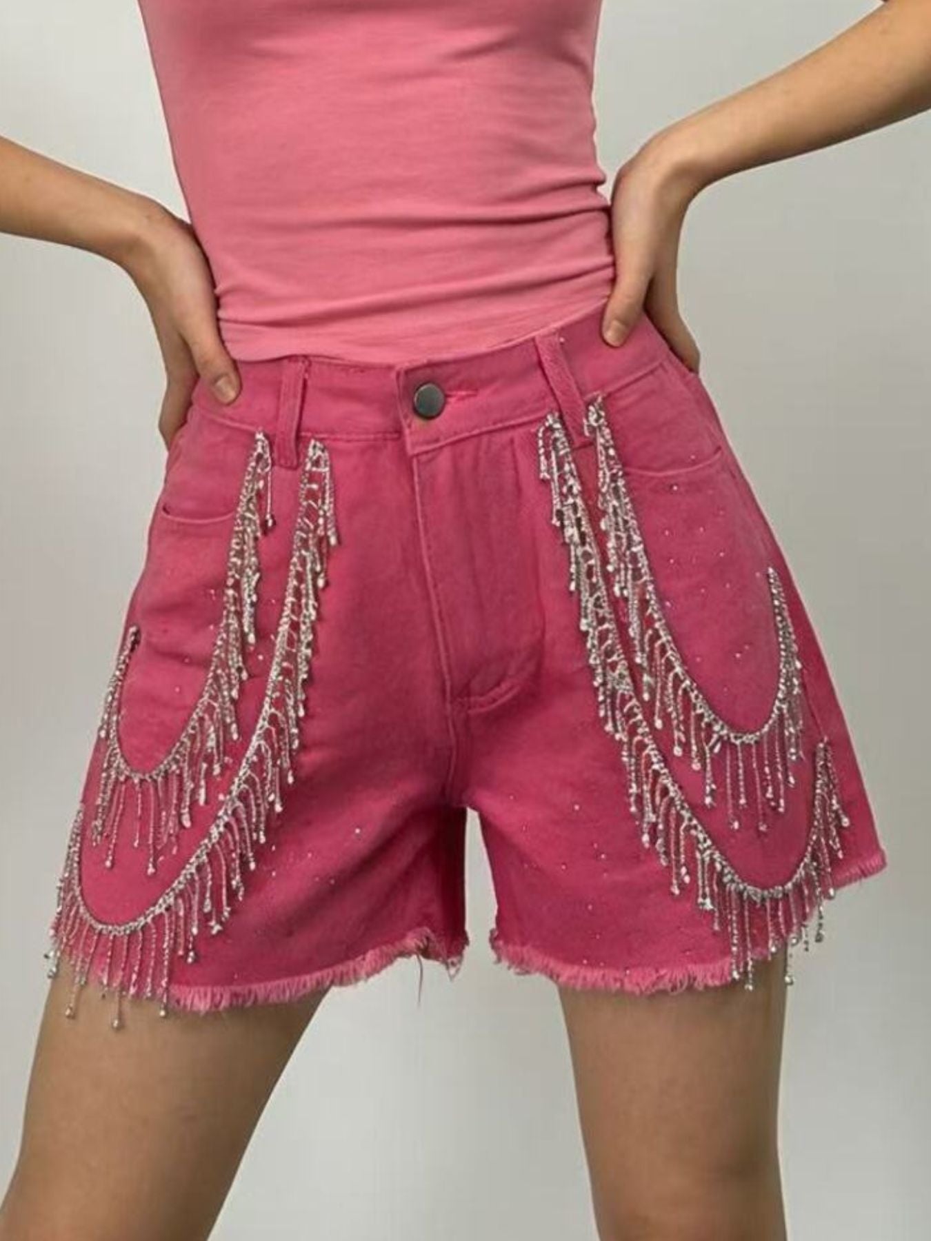 Fuchsia pink denim shorts with rhinestone chain fringe detail and frayed hem.