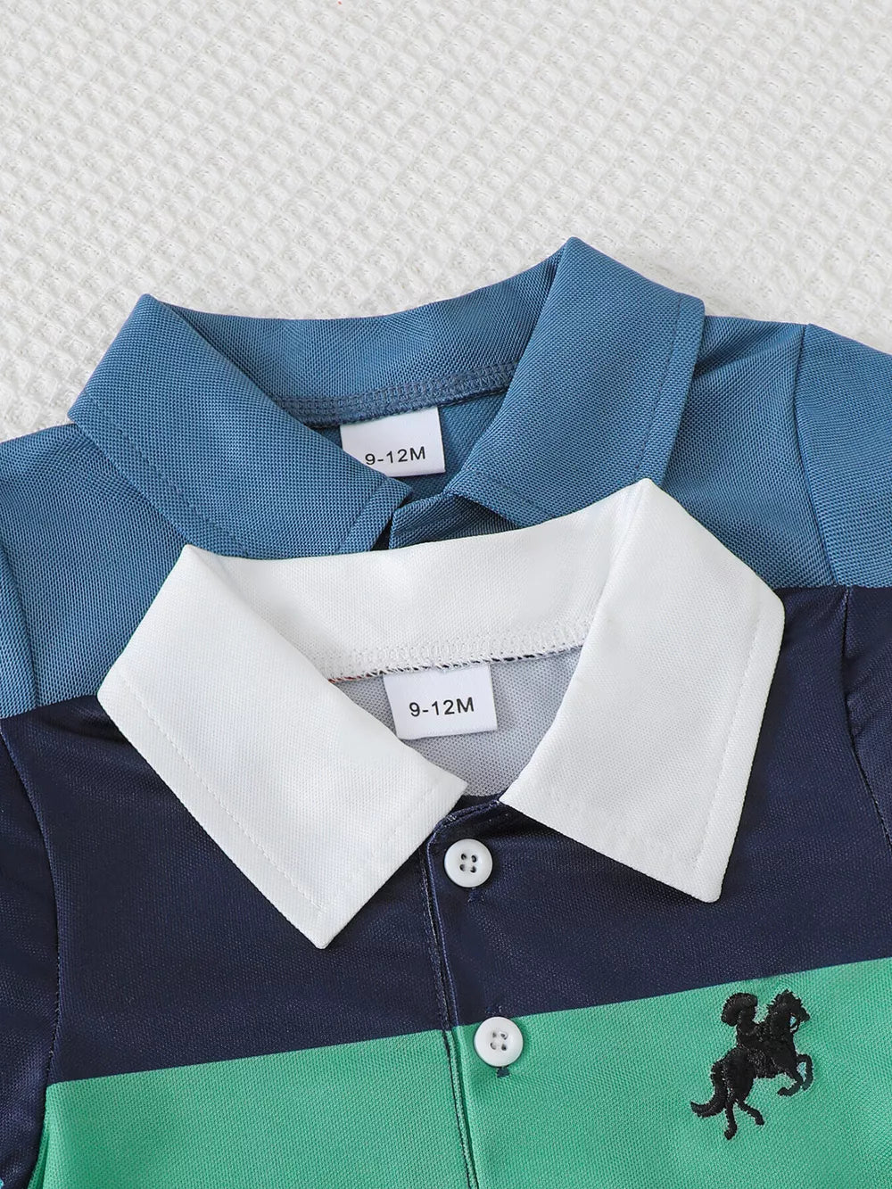 Color block polo romper for baby with navy, green, and blue stripes and horse embroidery.
