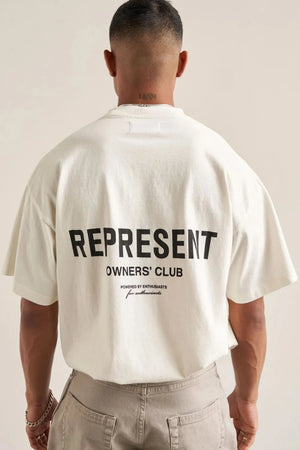 Oversized ivory graphic tee with black "REPRESENT OWNERS' CLUB" text and script detail.