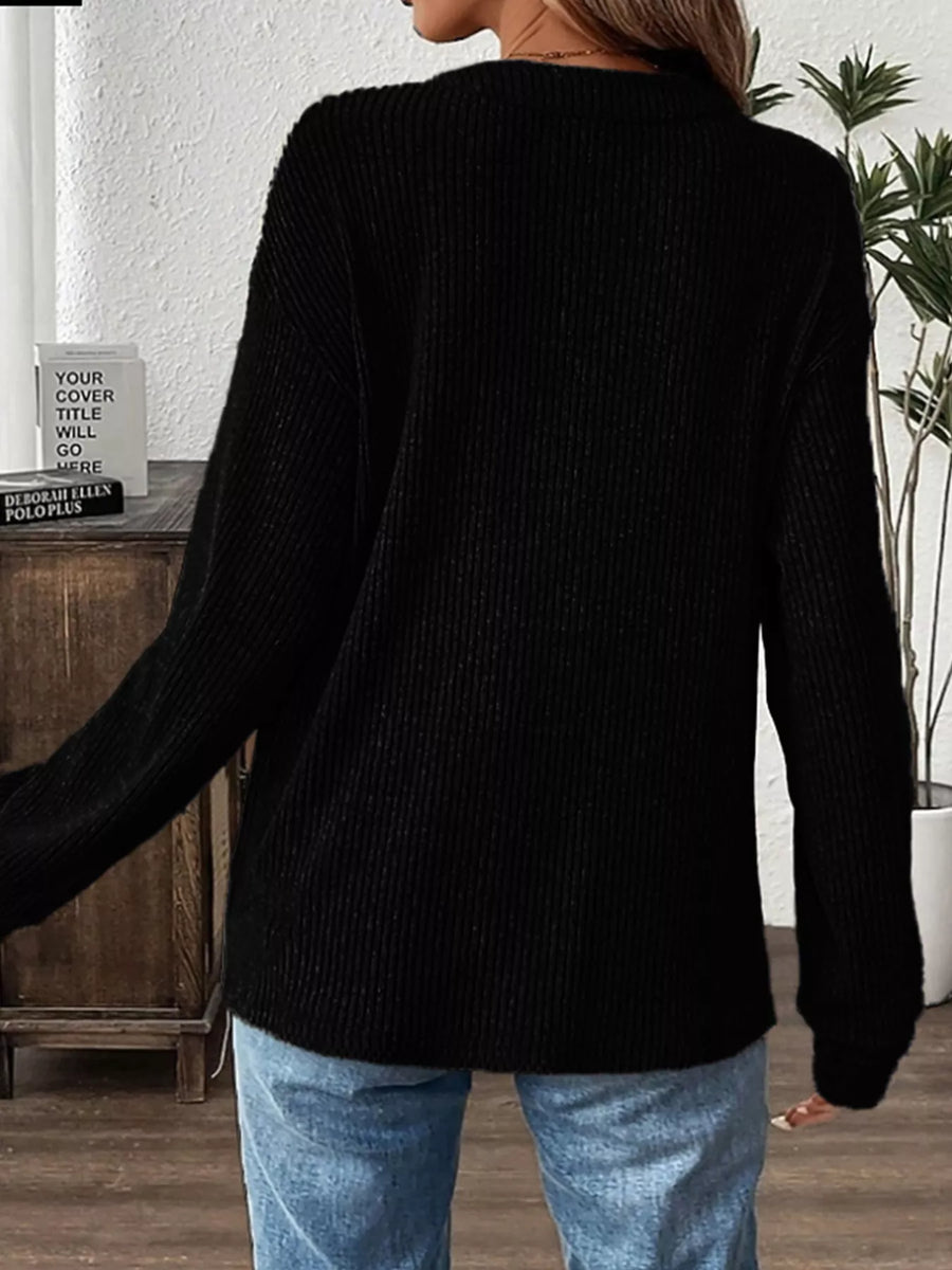 Black ribbed long-sleeve top with button detail, styled with jeans.