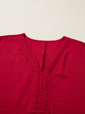 Braided V-neck red blouse with textured fabric and half sleeves.
