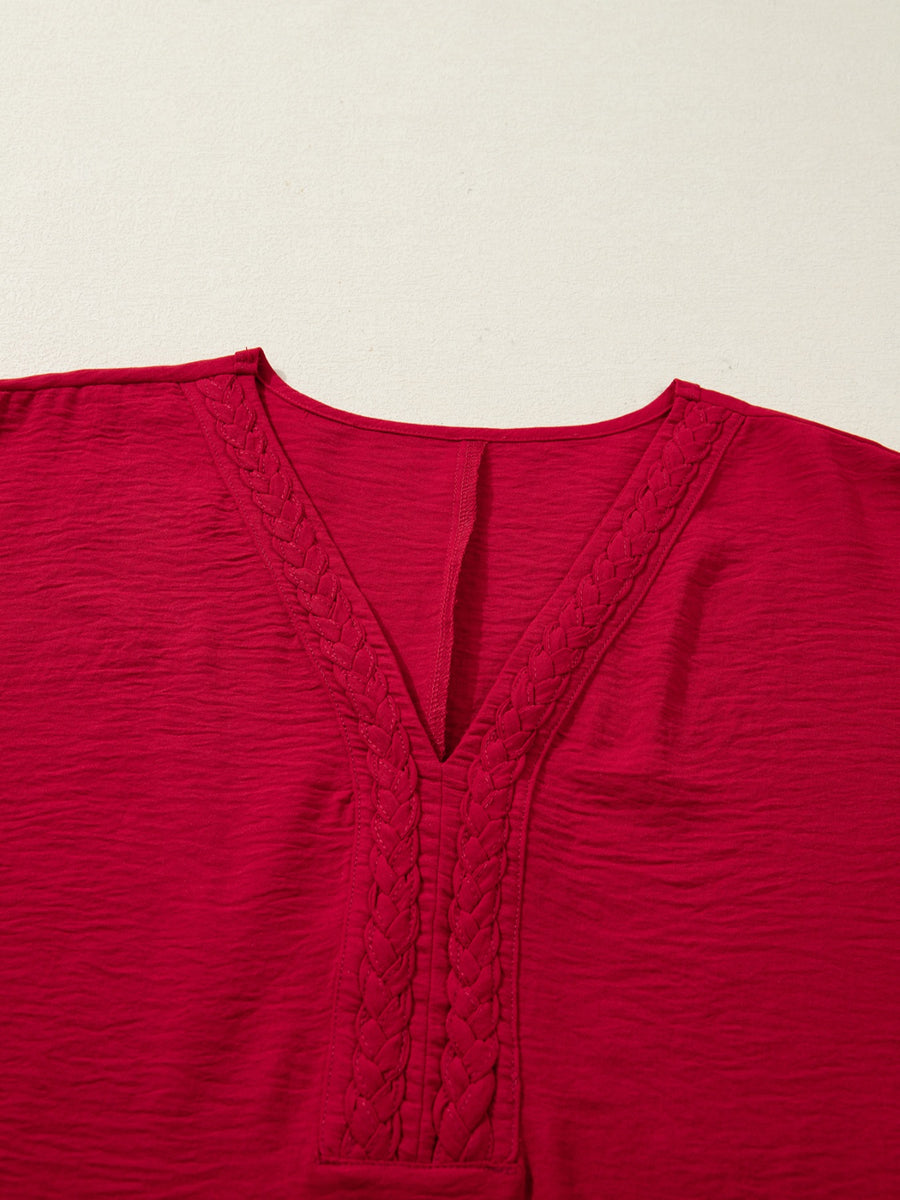 Braided V-neck red blouse with textured fabric and half sleeves.
