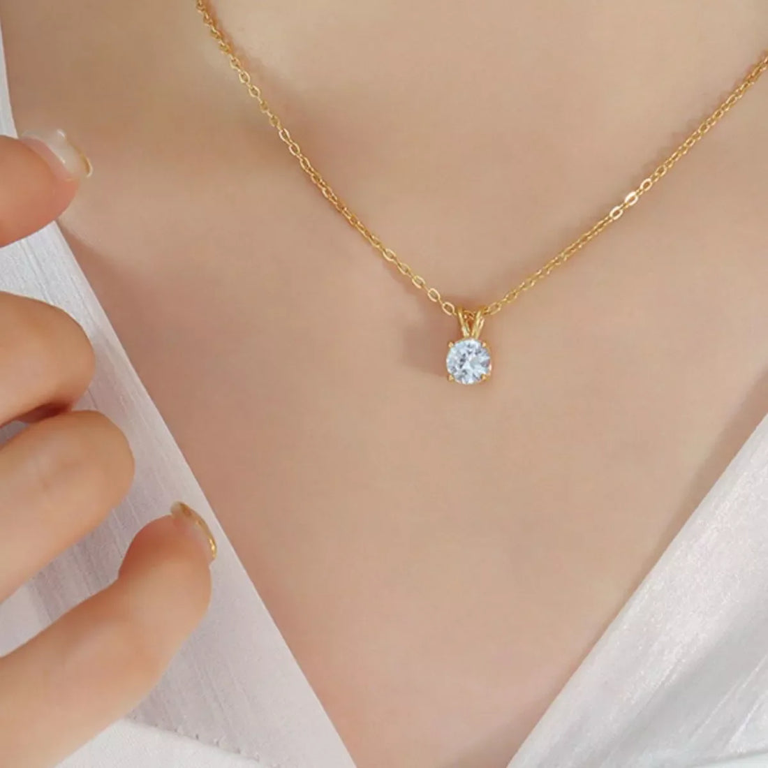 Gold chain necklace with a single round clear zircon pendant.