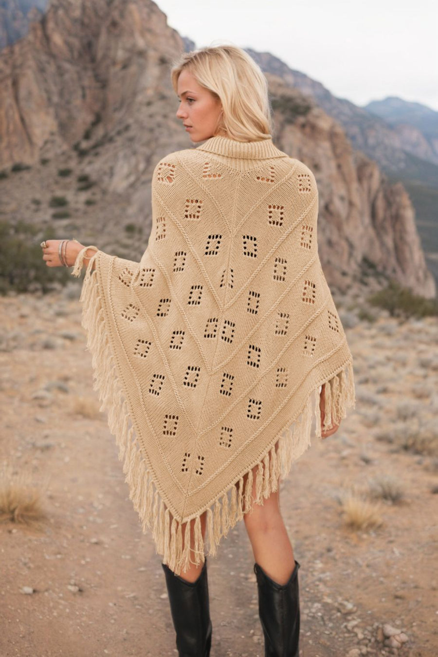 Tan knit poncho with geometric pattern and fringe, styled with black boots.