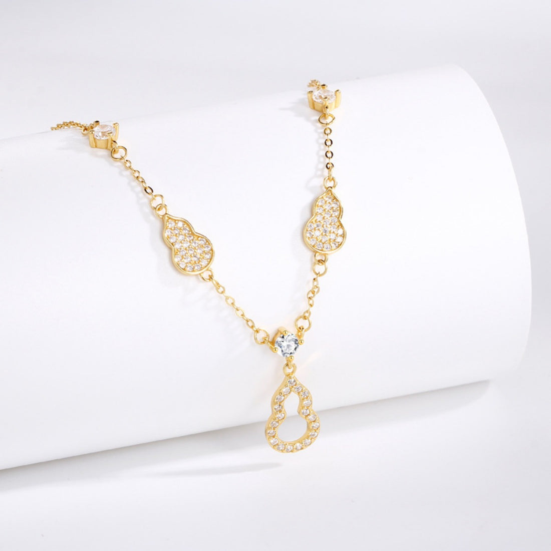 Gold Y-lariat necklace with zircon adorned gourd charms and a central teardrop pendant.