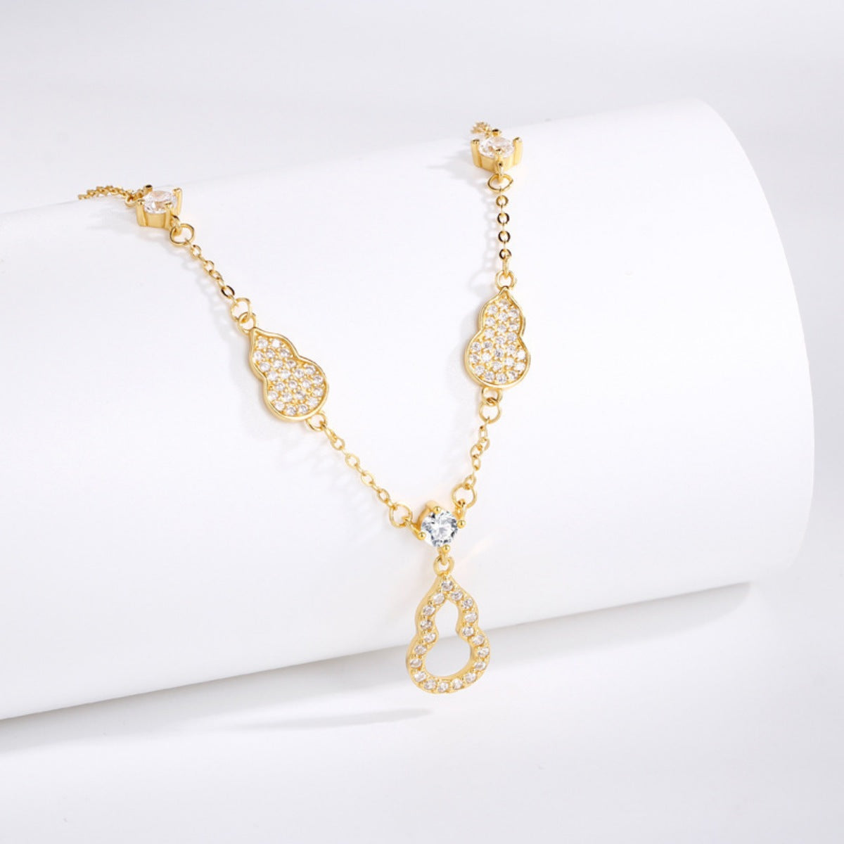 Gold Y-lariat necklace with zircon adorned gourd charms and a central teardrop pendant.