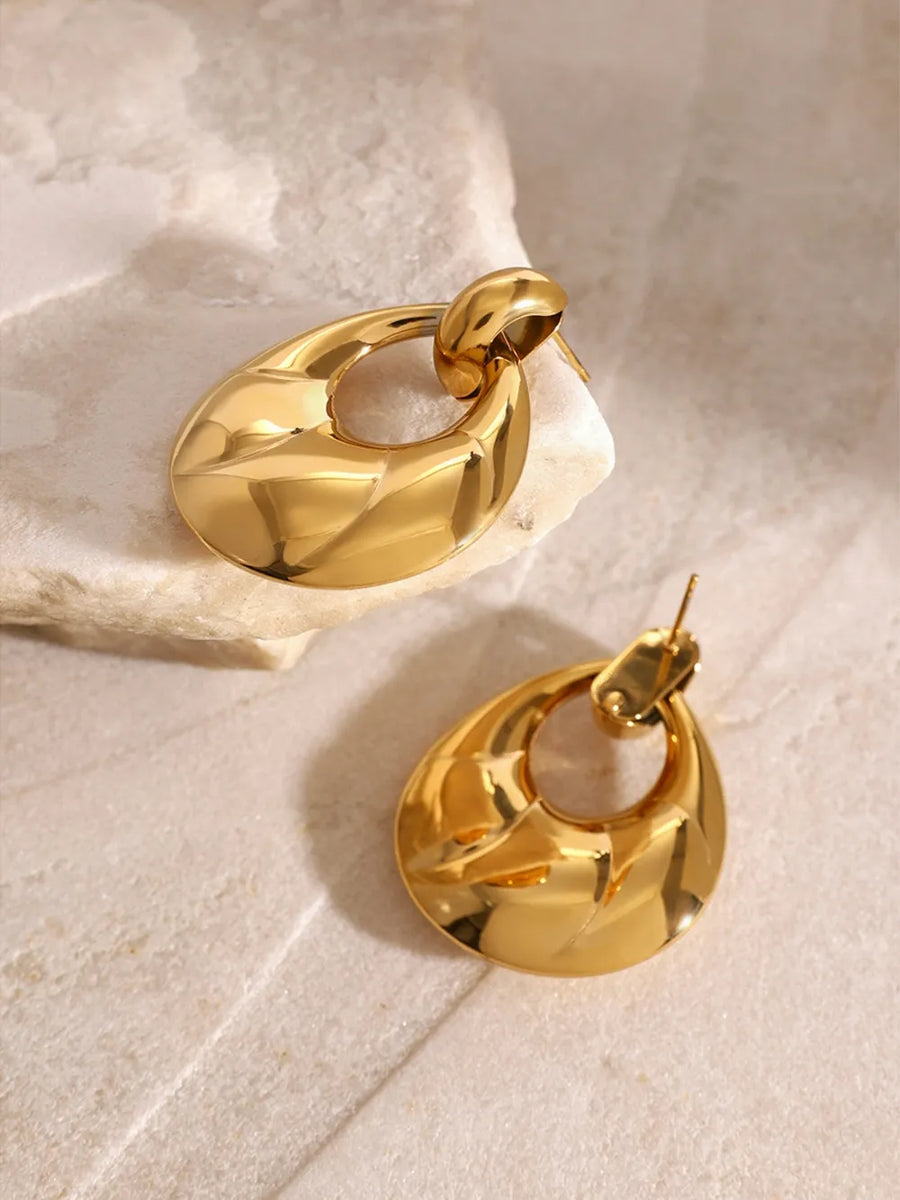 Gold sculpted statement earrings with a textured, abstract oval drop design.